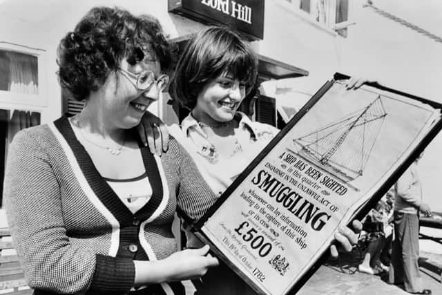 August 29, 1977, the caption pasted on the back reads: 'No smuggling at the inn... Miss Deborah Lloyd, left, and Miss Debbie Jarvis, of Broseley, view this unusual poster on display at the Lord Hill Inn, Broseley, this week.' The poster is dated October 19, 1782, and offers a reward for the capture of smugglers. 