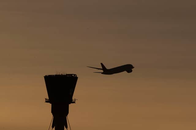 A plane takes off past the control tower at Heathrow Airport