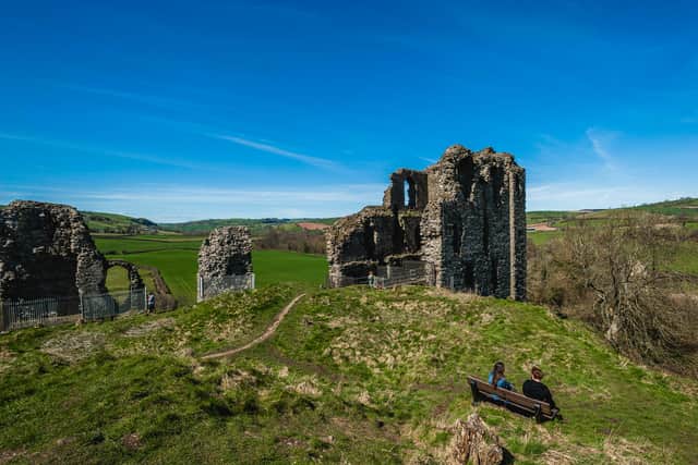 People looking into the distance from the top of Clun Castle in 2015, making the most of the sunny weather