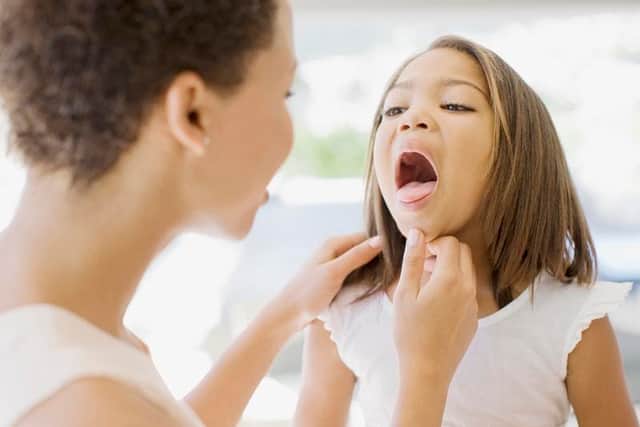 A mother checks her daughter's tongue