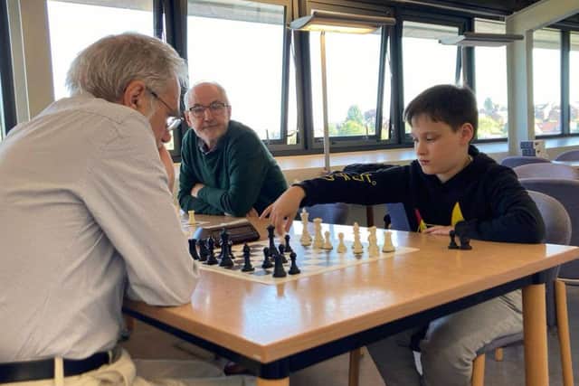 11-year-old Finlay makes his move watched by the more experienced players.