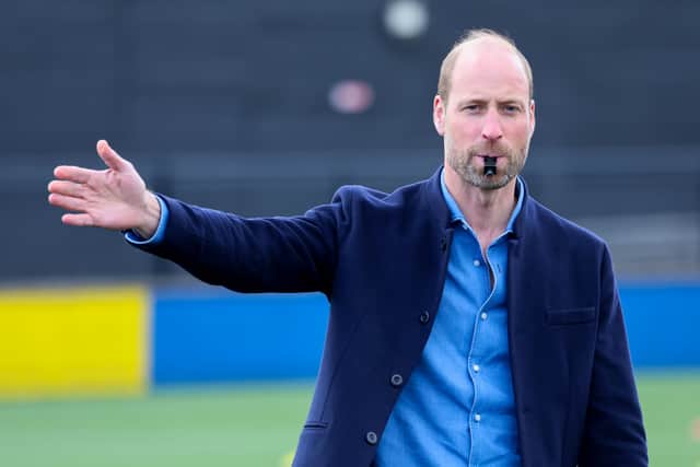 The Prince of Wales blows the referee's whistle during a mini football game.