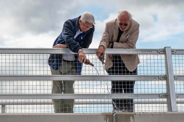 Project volunteers Roger Bravey and Phil Parker 'christen' the new bridge.