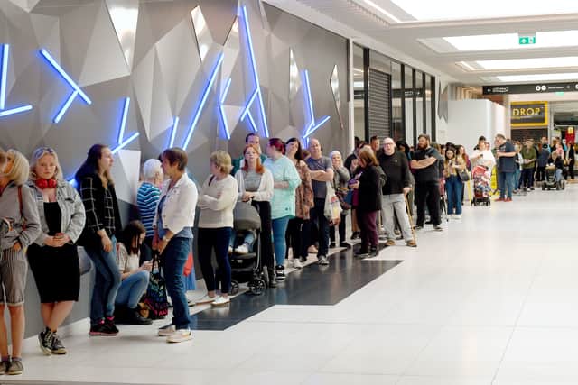 A large queue of people wait for the store to open