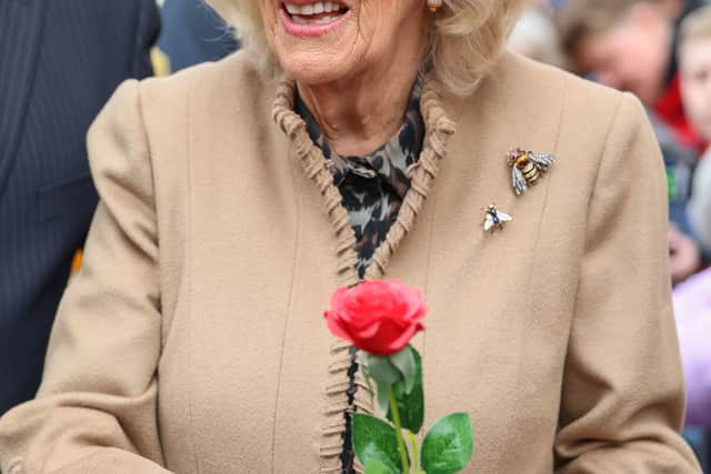 Queen Camilla smiles after receiving a red rose from Abi Crighton.