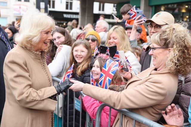 Queen Camilla smiles and shakes hands with well-wishers.