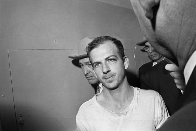 Lee Harvey Oswald is led down a corridor of the Dallas police station for another round of questioning in connection with the assassination of U.S, President John F. Kennedy