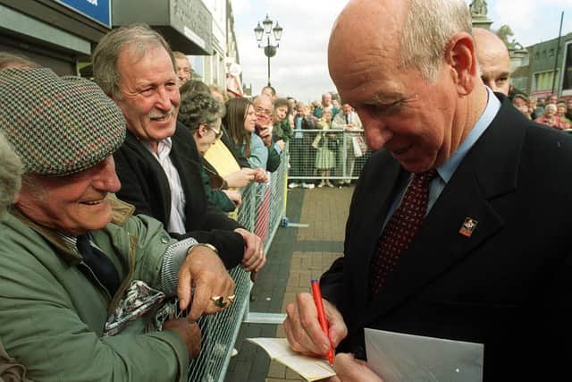 Sir Bobby Charlton signing Lawrence Walker's pension book in Dudley after the unveiling of the Duncan Edwards statue in 1999