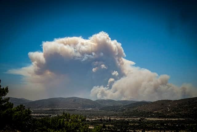 A cloud of smoke from a forest fire rises over the island of Rhodes on Saturday. Photo: Argyris Mantikos/Eurokinissi via AP.