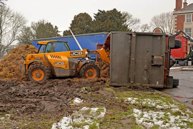 Tractors work to right the trailer and contain the remaining manure