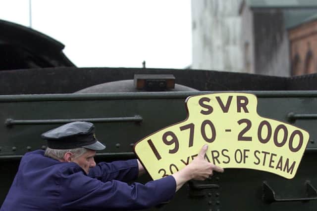 Severn Valley Railway volunteer Tony Bending fitting an anniversary sign on to an engine