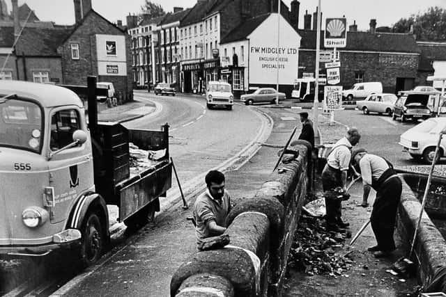 The canal bridge at the bottom of the High Street, an ancient monument, was damaged badly when it was hit by a car in 1974. County council workers were photographed repairing it the following week