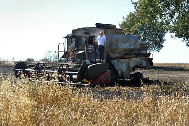 Farmer Tim Ashton with the burnt-out husk of his combine harvester