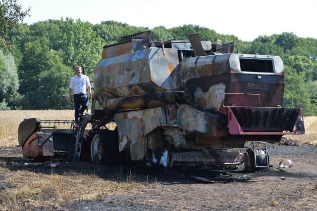Farmer Tim Ashton with the burnt-out husk of his combine harvester