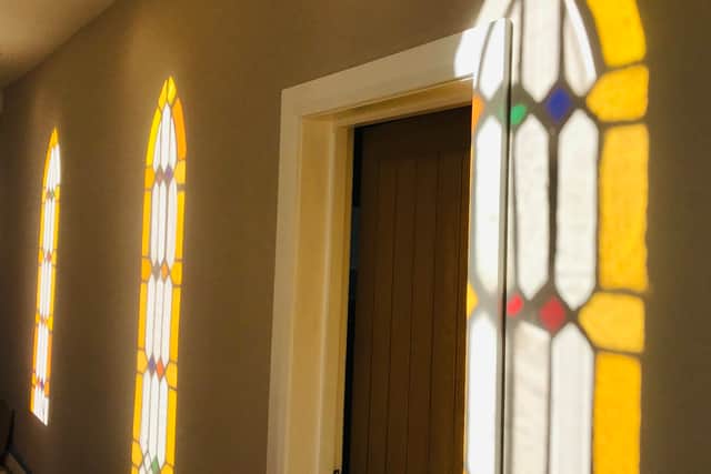 The church's stained glass windows reflect on an interior wall.