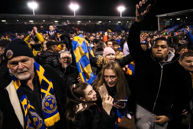 Fans of Shrewsbury Town celebrate on the pitch at full time. Photo: AMA