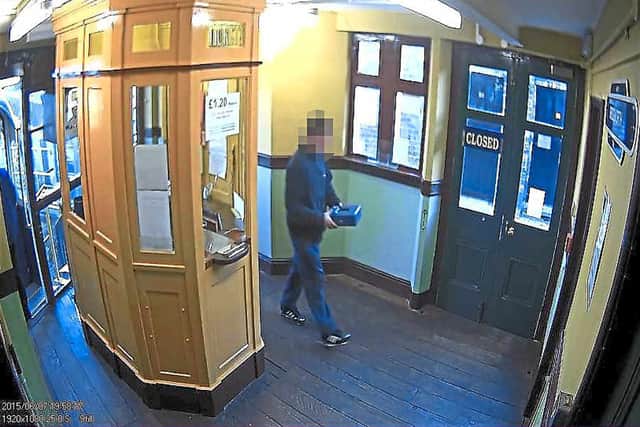 A man is seen taking away the blue cash box