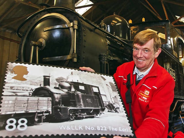 Welshpool postman Nick Thomas with an 88p landscape stamp of steam locomotive The Earl No822