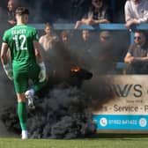 Josh Gracey of AFC Telford United kicks a smoke flare thrown on to the pitch away