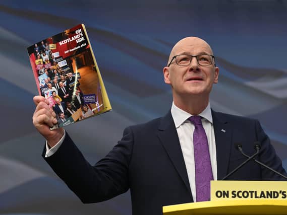 John Swinney holding up a copy of the SNP manifesto