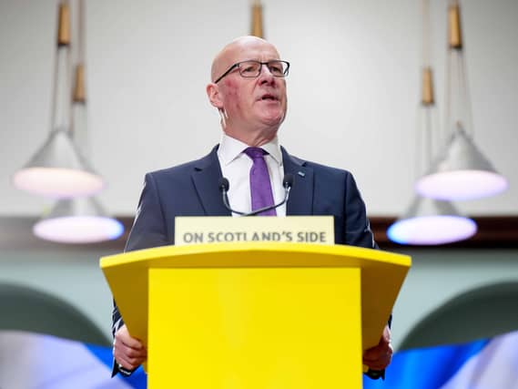 John Swinney speaking from an SNP lectern