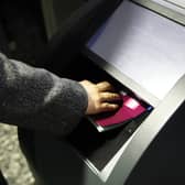A hand pressing an open passport into a machine to be scanned