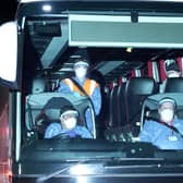 People on a coach wearing protective suits and facemasks