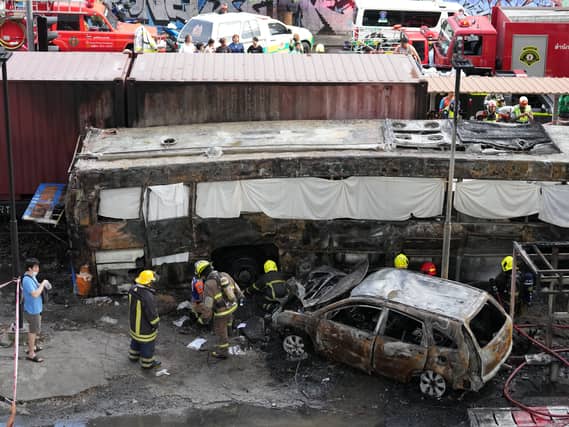 Rescuers work on a charred shell of a bus after a terrible tragedy