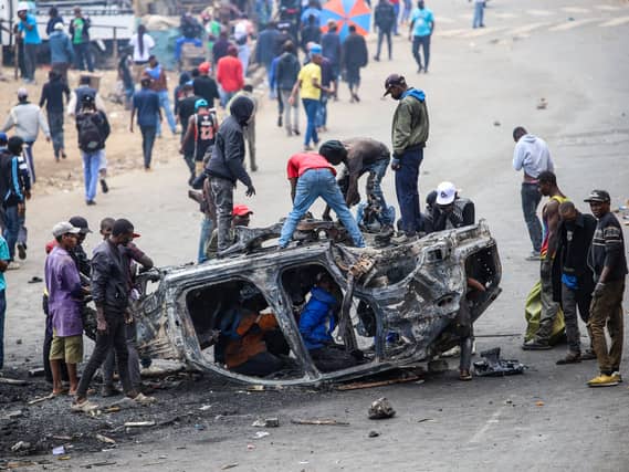 People strip parts from a burned-out vehicle during a public transport strike over fuel prices in Nairobi, Kenya