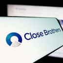Mobile phone with logo of British merchant bank company Close Brothers Group in front of website