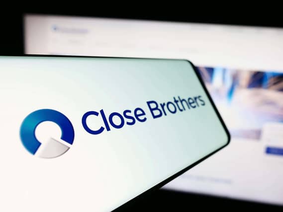 Mobile phone with logo of British merchant bank company Close Brothers Group in front of website