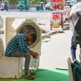 A man sits in front of a water cooler at a roadside cooling station in New Delhi, India