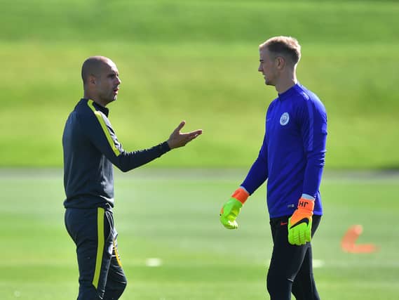 Manchester City manager Pep Guardiola talks to goalkeeper Joe Hart during a training session at the City Football Academy