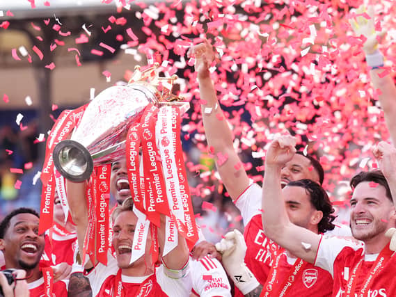 Arsenal’s Martin Odegaard lifts the Premier League trophy as confetti flies behind him