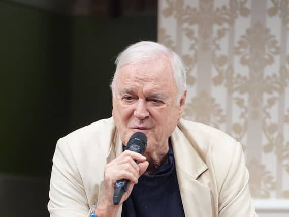 John Cleese with a microphone on stage