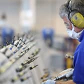 Factory workers using machinery, wearing masks and ear defenders