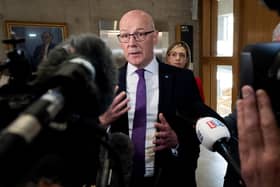 John Swinney speaking in front of a series of microphones and cameras