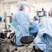 Surgeons look at a screen displaying an AI overlay of patient anatomy, including nerves and connective tissue during bowel resection surgery