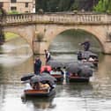 People on boats shelter from rain under umbrellas