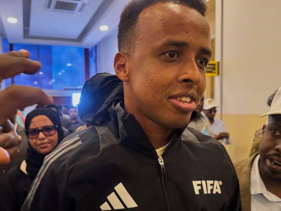 Referee Omar Artan, in a FIFA tracksuit jacket, arrives home in Somalia after being denied entry to the United States for the World Cup