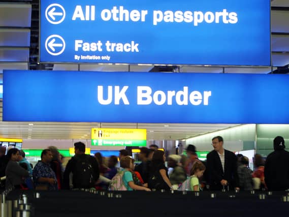 People in an airport under a UK Border sign