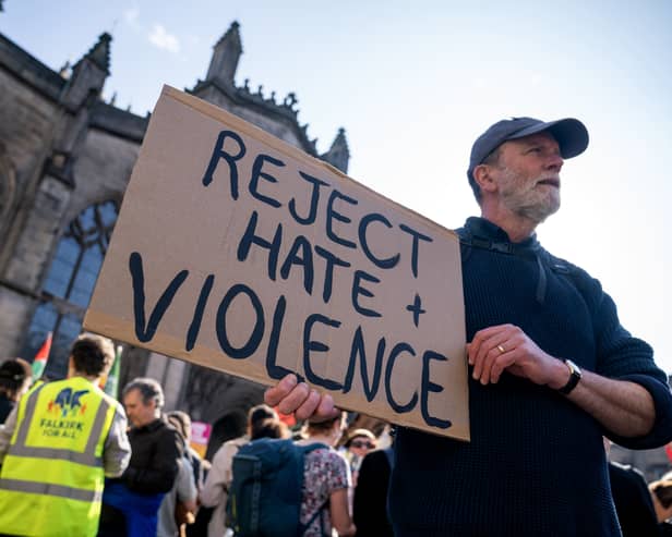 A man holding a sign reading 'Reject hate and violence'