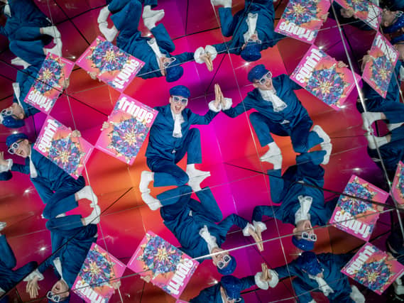 A performer holding a Fringe programme, reflected several times in giant kaleidoscope