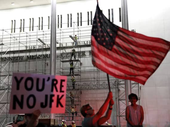 People wait for President Donald Trump’s name to be removed