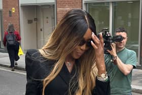 Naomi Campbell wearing sunglasses and shielding her face