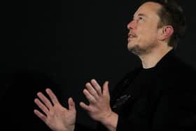 Elon Musk looking upwards and gesturing with his hands