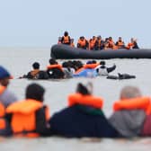 People thought to be migrants wade in the water as they attempt to board a small boat
