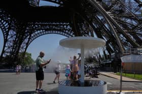 People cool off in a water spray near the Eiffel Tower in Paris