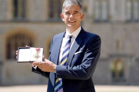 Matthew Brittin smiling while holding up his CBE medal