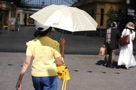 A woman uses an umbrella to shade herself from the sun as she walks in Windsor